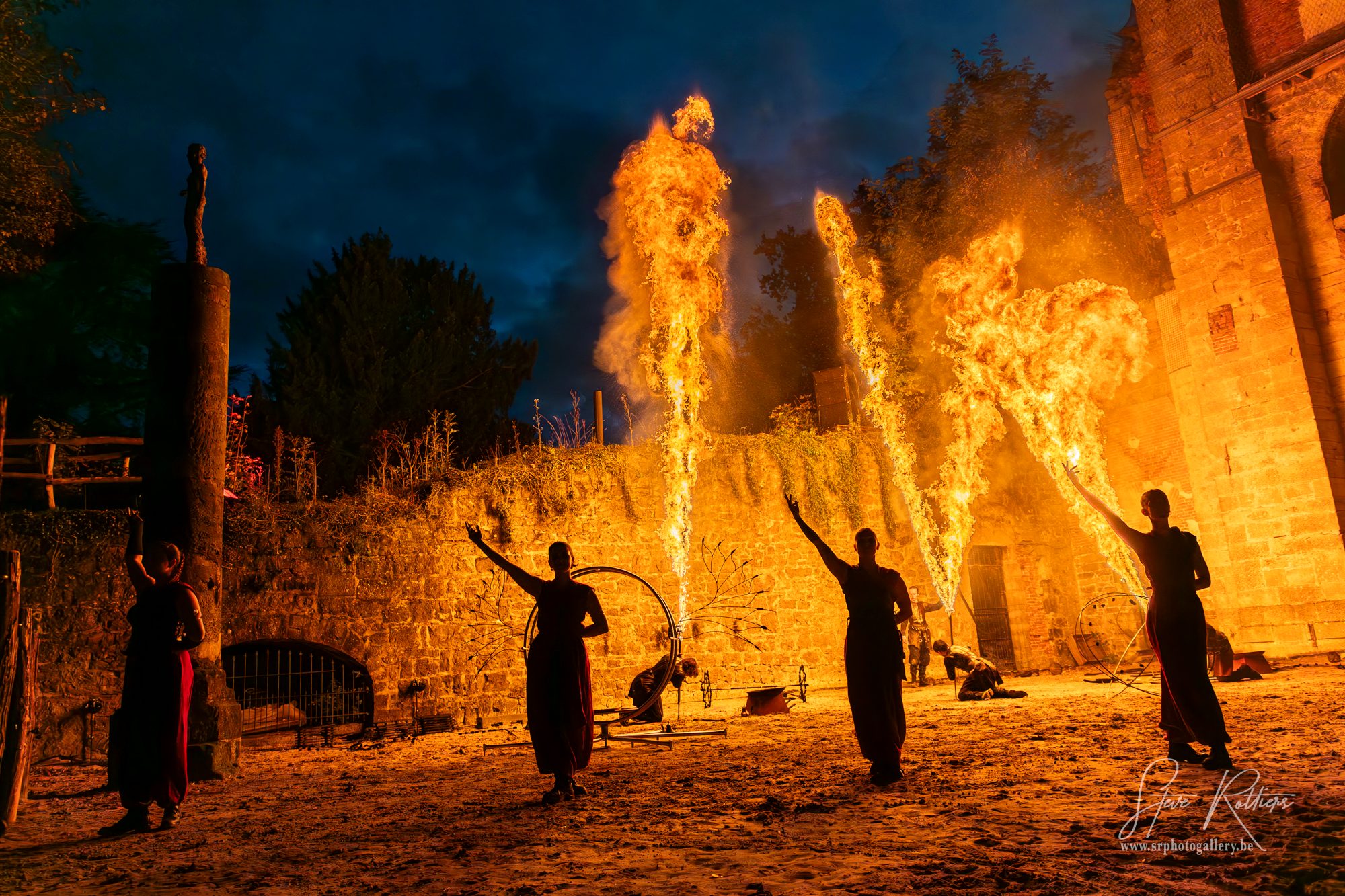 Trois artistes Pyronix crachant des flammes devant un mur en ruines